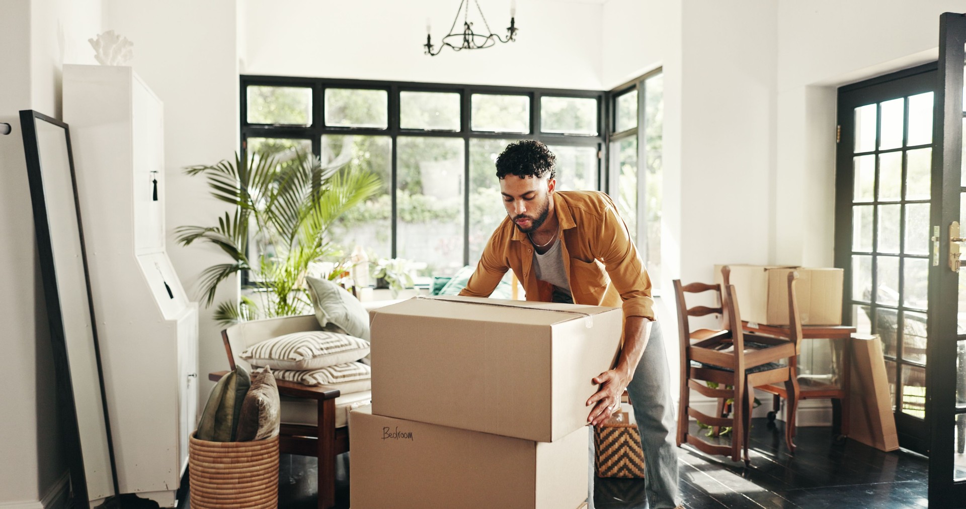 Neues Haus, Umzug und Mann mit Kisten, Immobilien und Eigentum an Immobilien mit Hypothek oder Lounge. Umzug, Käufer und Person mit Pappe im Wohnzimmer, Investition und Kauf mit Wohnungsbaudarlehen